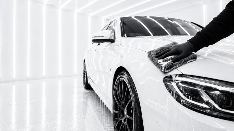 Detailer drying a car hood with a microfiber towel after a hand wash