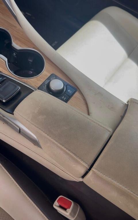 Cream leather center console with dirt and stains before detailing